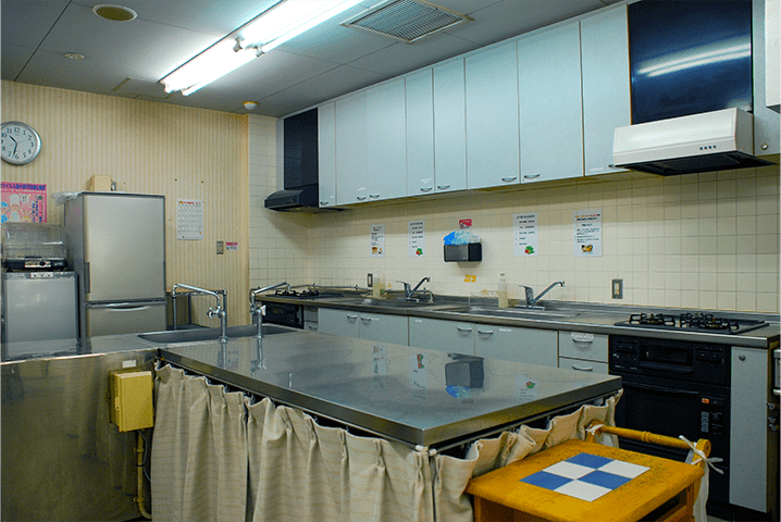 調理室の写真です。手前に調理台があり左手奥に冷蔵庫右手奥にシンクとガスコンロがあります。