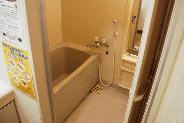  入室の写真です。右に鏡真ん中にシャワーヘッド左側にバスタブがあります。